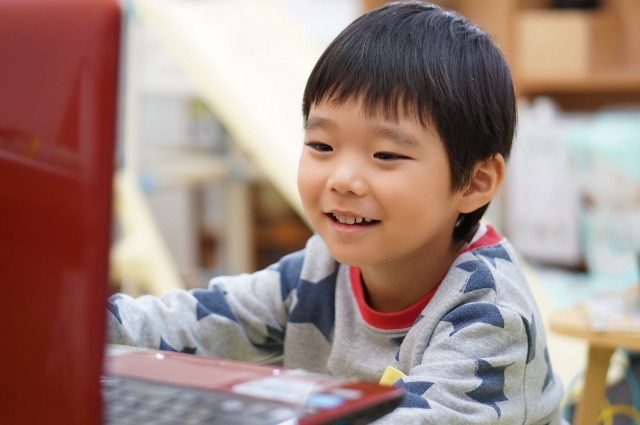 笑顔でノートパソコンに向かう男の子