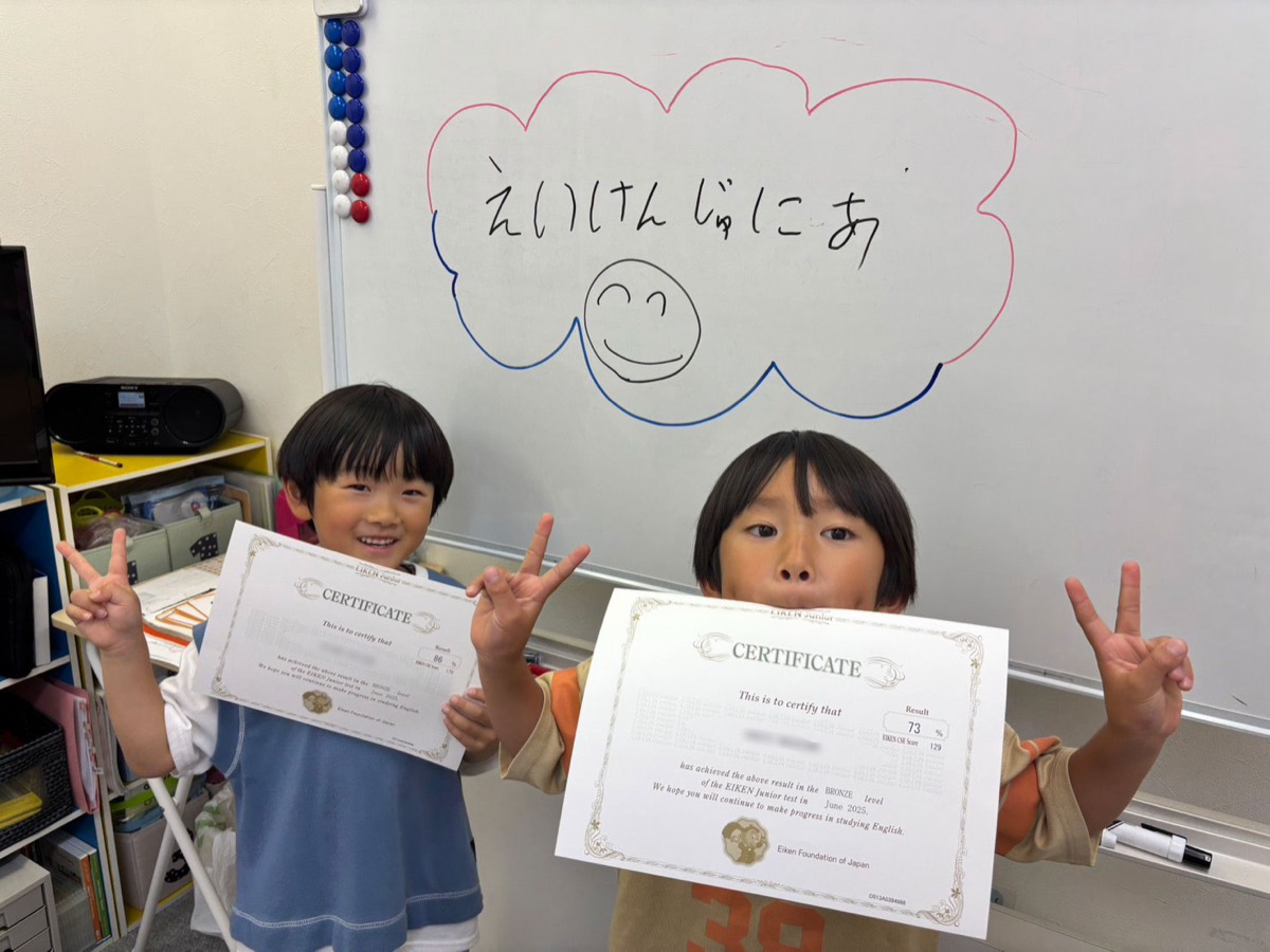 英検Jr. の合格証を手に、ピースをする子どもたち